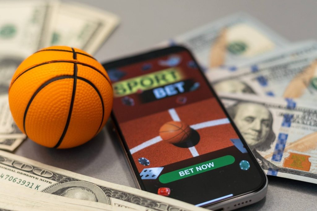 Sports betting website in a mobile phone screen, ball, money